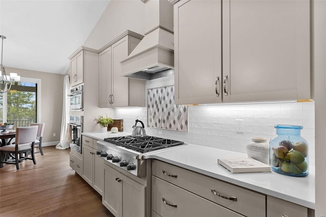 kitchen with dark hardwood / wood-style floors, decorative light fixtures, backsplash, stainless steel appliances, and custom range hood