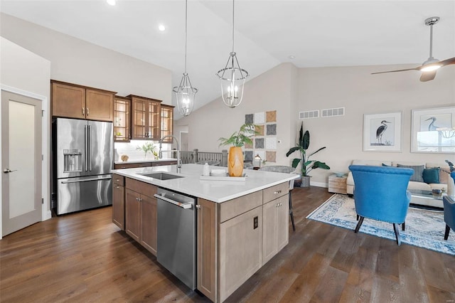 kitchen with dark hardwood / wood-style floors, decorative light fixtures, sink, stainless steel appliances, and a center island with sink