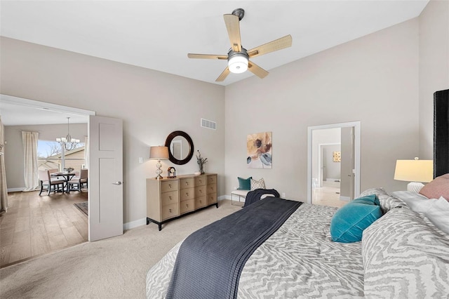 carpeted bedroom with ceiling fan with notable chandelier, connected bathroom, and high vaulted ceiling