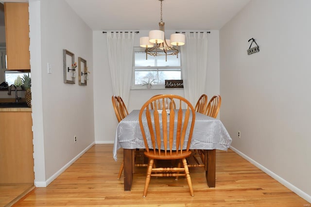 dining room with sink, a notable chandelier, and light wood-type flooring