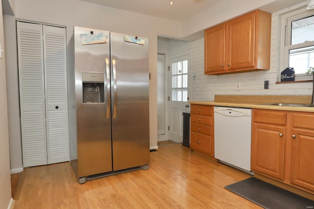 kitchen with sink, light hardwood / wood-style flooring, dishwasher, backsplash, and stainless steel fridge with ice dispenser