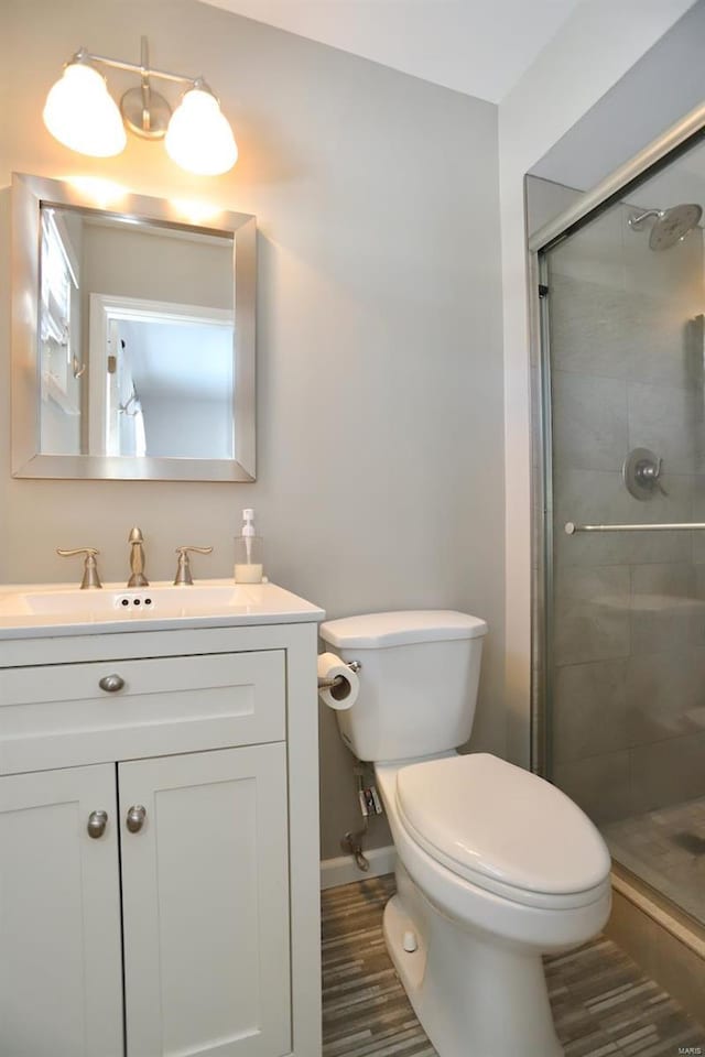 bathroom with hardwood / wood-style flooring, vanity, toilet, and a shower with shower door