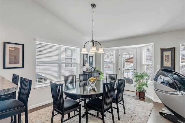 dining space featuring vaulted ceiling, hardwood / wood-style floors, and an inviting chandelier