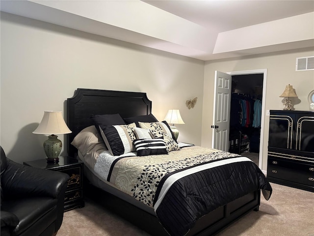 bedroom featuring a walk in closet, light carpet, and a closet