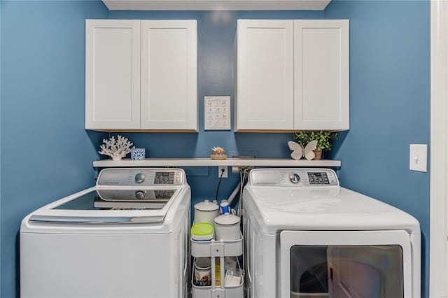 clothes washing area featuring cabinets and independent washer and dryer