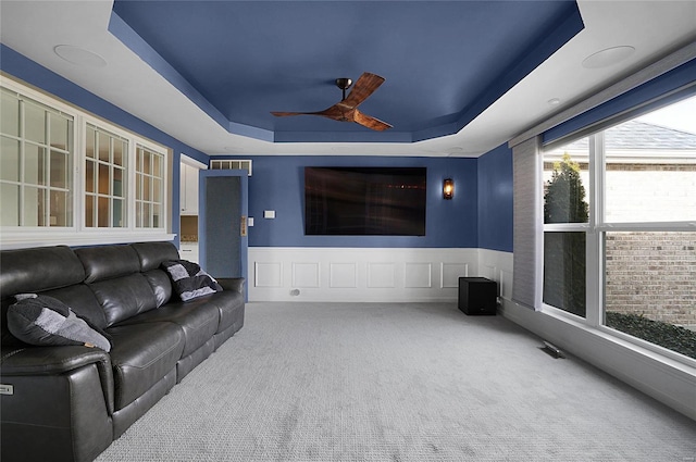 unfurnished living room with ceiling fan, a raised ceiling, and carpet