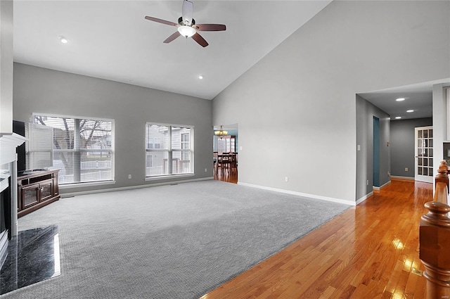 unfurnished living room featuring ceiling fan, a premium fireplace, high vaulted ceiling, and carpet flooring