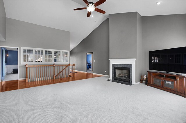 carpeted living room featuring a high end fireplace, high vaulted ceiling, and ceiling fan