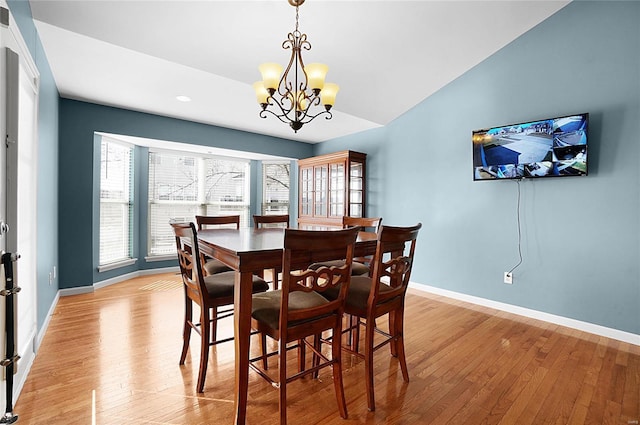 dining space featuring an inviting chandelier, lofted ceiling, and light wood-type flooring