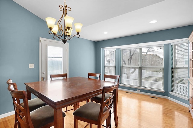 dining space featuring light hardwood / wood-style flooring and a chandelier