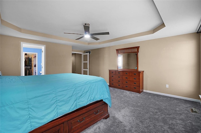 carpeted bedroom with a tray ceiling, a closet, ceiling fan, and a spacious closet