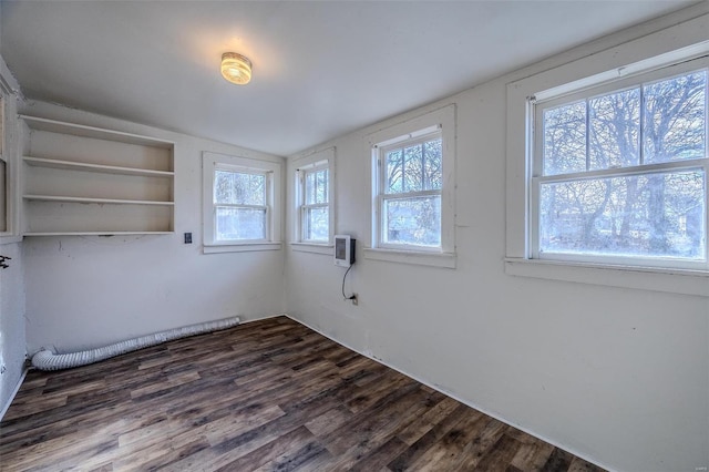 spare room with lofted ceiling, dark wood-type flooring, a wealth of natural light, and an AC wall unit