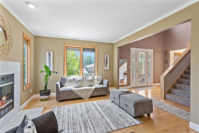 living room featuring a tile fireplace, ornamental molding, and light hardwood / wood-style flooring