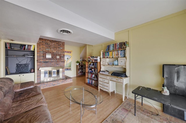 living area featuring a fireplace, wood finished floors, and visible vents