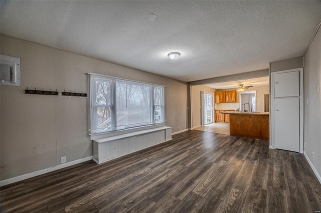 unfurnished living room featuring dark hardwood / wood-style floors, sink, and a textured ceiling