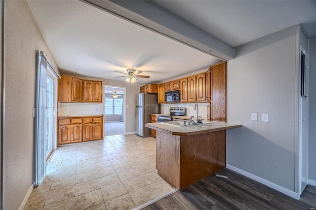 kitchen with sink, light tile patterned floors, ceiling fan, kitchen peninsula, and stainless steel appliances