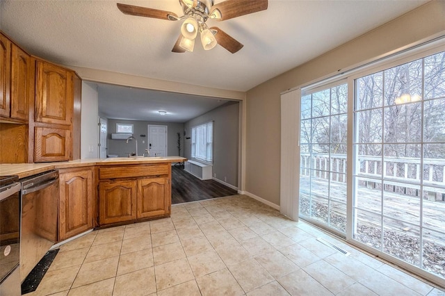 kitchen featuring sink, a wealth of natural light, stainless steel dishwasher, and light tile patterned flooring