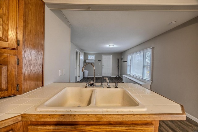 kitchen with sink, tile countertops, dark hardwood / wood-style flooring, and kitchen peninsula