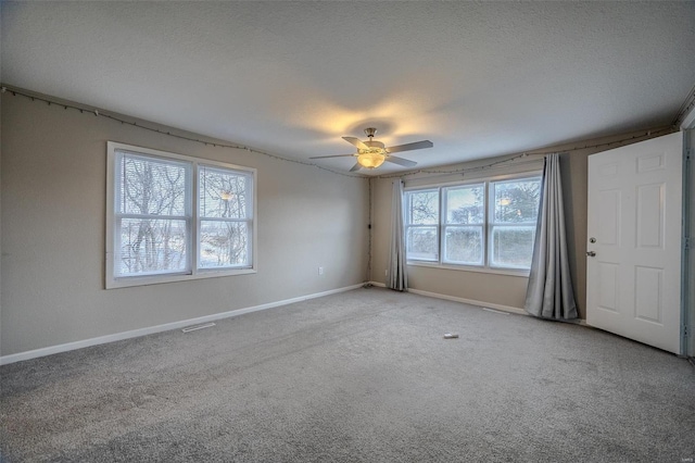 empty room with ceiling fan, carpet, and a textured ceiling