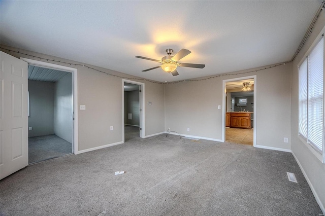 unfurnished bedroom with ceiling fan, connected bathroom, and light carpet