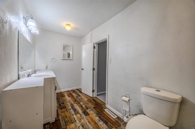 bathroom featuring vanity, toilet, hardwood / wood-style floors, and a textured ceiling