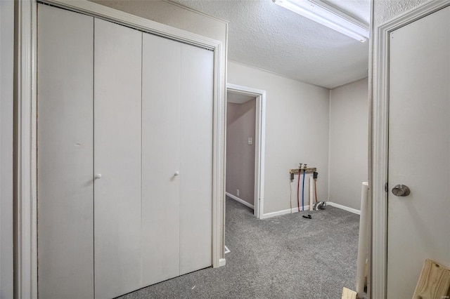 corridor with light carpet and a textured ceiling