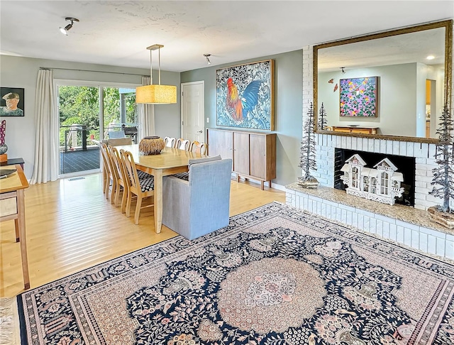 dining room with a brick fireplace and light hardwood / wood-style flooring