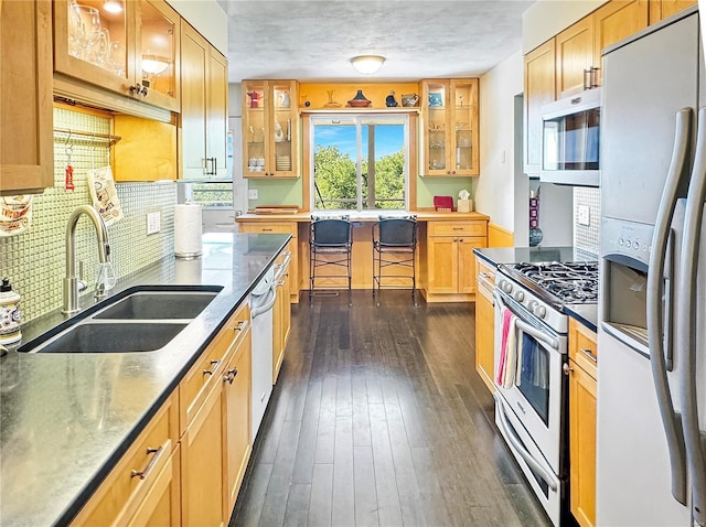 kitchen with gas stove, sink, fridge with ice dispenser, tasteful backsplash, and dark hardwood / wood-style flooring