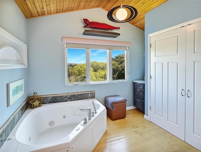 bathroom with wood-type flooring, vaulted ceiling, a bathtub, and wood ceiling