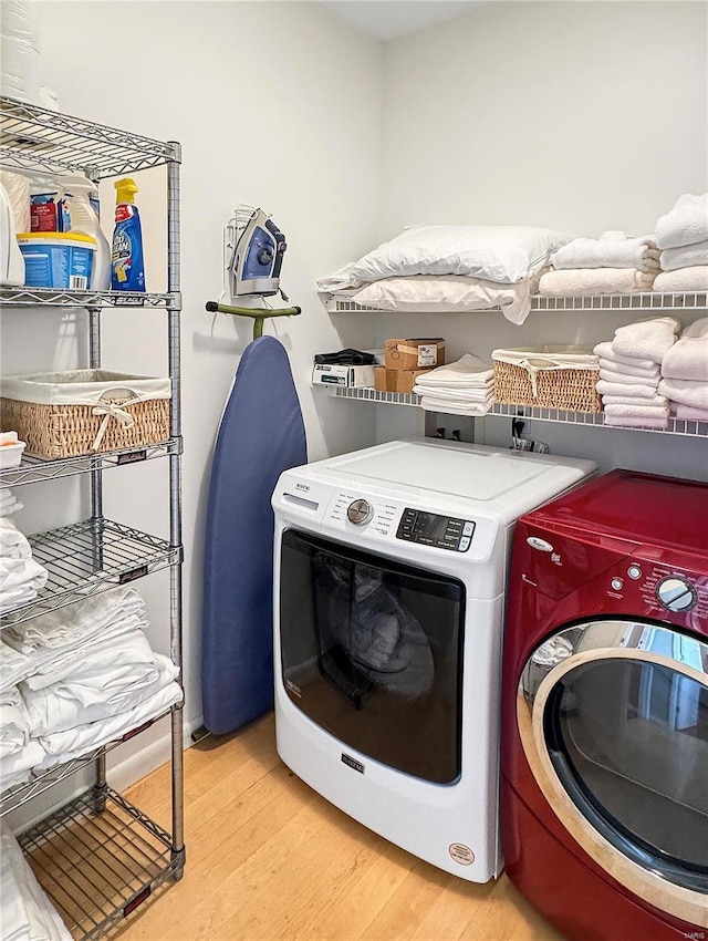 clothes washing area with independent washer and dryer and light hardwood / wood-style flooring