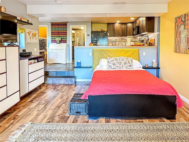 bedroom with black refrigerator and light hardwood / wood-style flooring