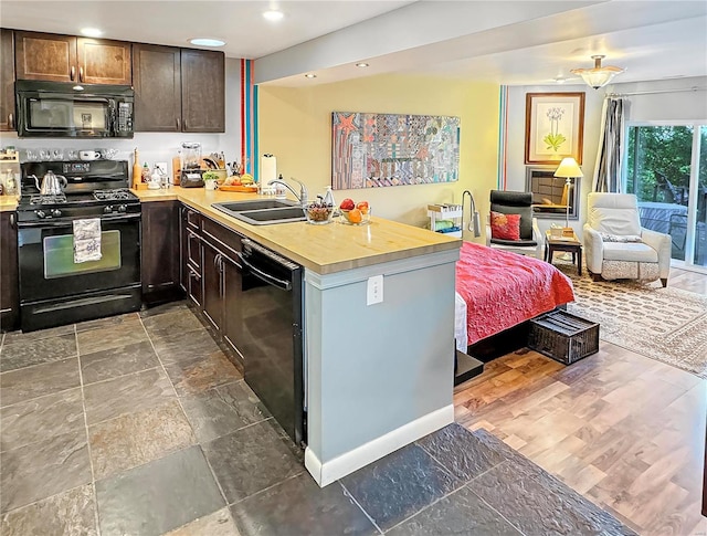 kitchen with kitchen peninsula, sink, dark brown cabinets, and black appliances