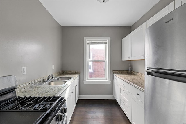 kitchen featuring sink, dark wood-type flooring, appliances with stainless steel finishes, light stone countertops, and white cabinets