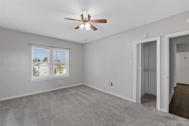 unfurnished bedroom with carpet flooring, heating unit, a textured ceiling, and a closet