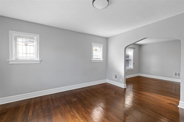 empty room with a textured ceiling and dark hardwood / wood-style flooring