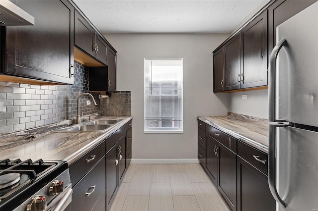 kitchen with sink, stainless steel fridge, dark brown cabinetry, tasteful backsplash, and a textured ceiling