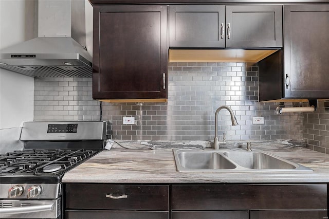 kitchen featuring sink, decorative backsplash, wall chimney range hood, dark brown cabinets, and stainless steel range with gas stovetop