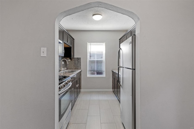 kitchen with sink, backsplash, a textured ceiling, and appliances with stainless steel finishes