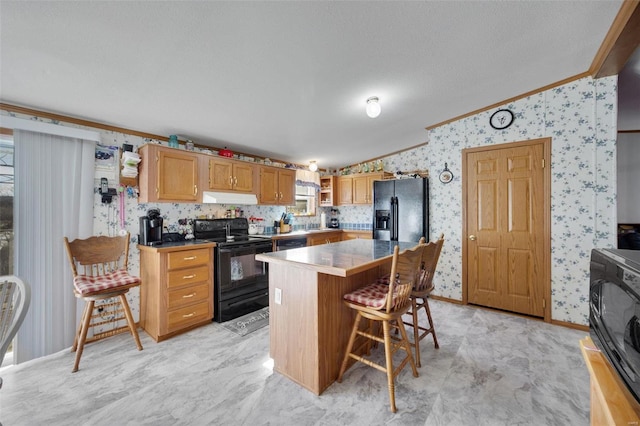 kitchen featuring a breakfast bar, crown molding, a textured ceiling, a kitchen island, and black appliances