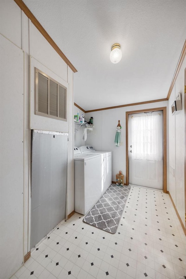 clothes washing area featuring washer and clothes dryer, ornamental molding, and a textured ceiling