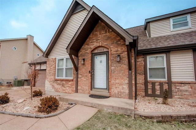 view of front of home featuring a shingled roof and brick siding