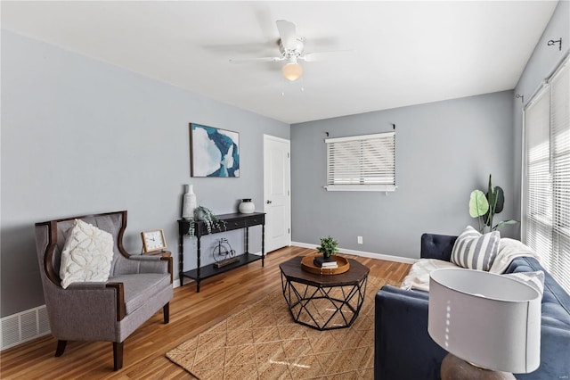 living room featuring a ceiling fan, baseboards, visible vents, and wood finished floors