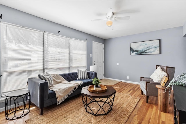 living room featuring ceiling fan, light wood finished floors, and baseboards