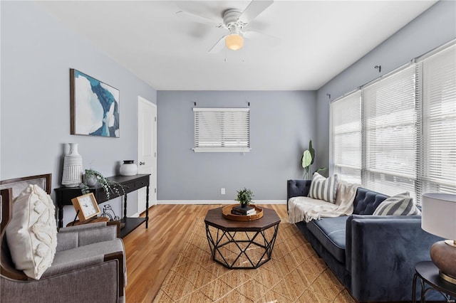 living room featuring a ceiling fan, baseboards, and wood finished floors