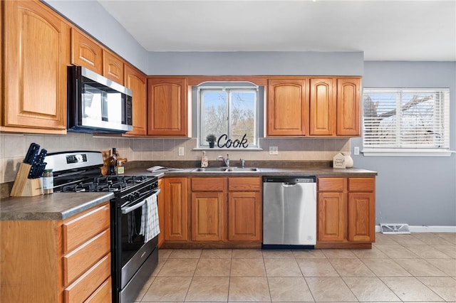 kitchen featuring appliances with stainless steel finishes, dark countertops, and a sink