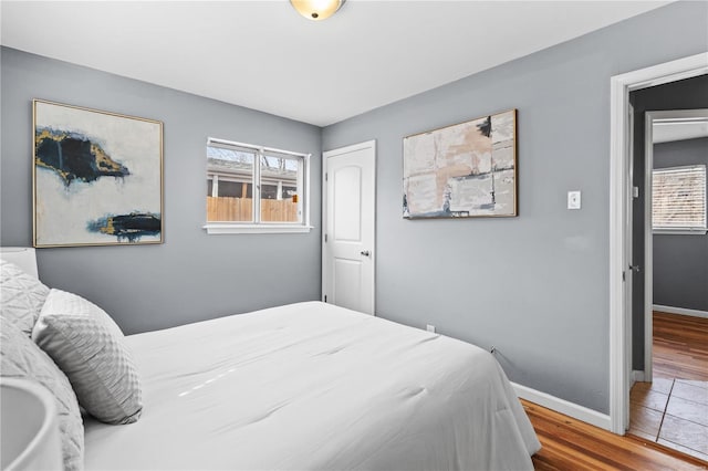 bedroom featuring multiple windows, wood finished floors, and baseboards