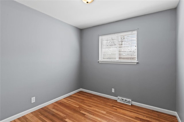 spare room featuring baseboards, visible vents, and wood finished floors