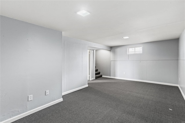 basement with dark colored carpet, baseboards, and stairs