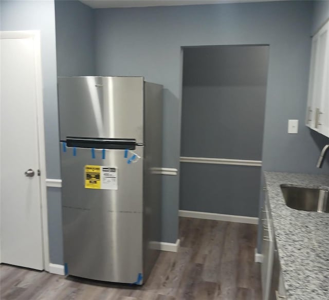 kitchen with stainless steel refrigerator, sink, white cabinets, dark hardwood / wood-style flooring, and light stone countertops