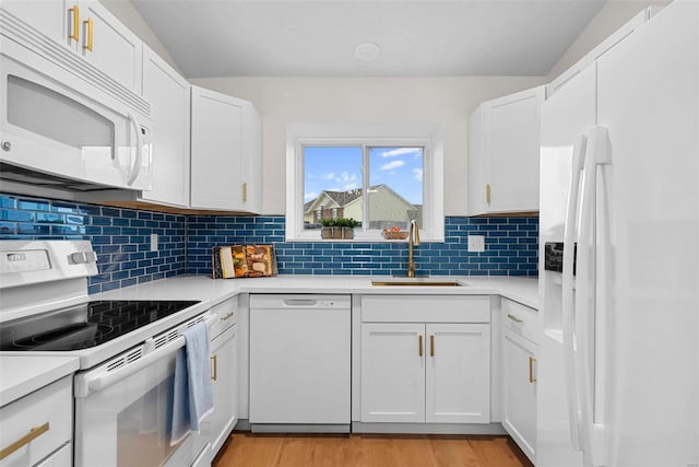 kitchen with tasteful backsplash, white cabinetry, sink, white appliances, and light hardwood / wood-style flooring